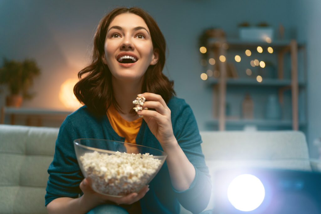 Young woman watching projector, TV, movies